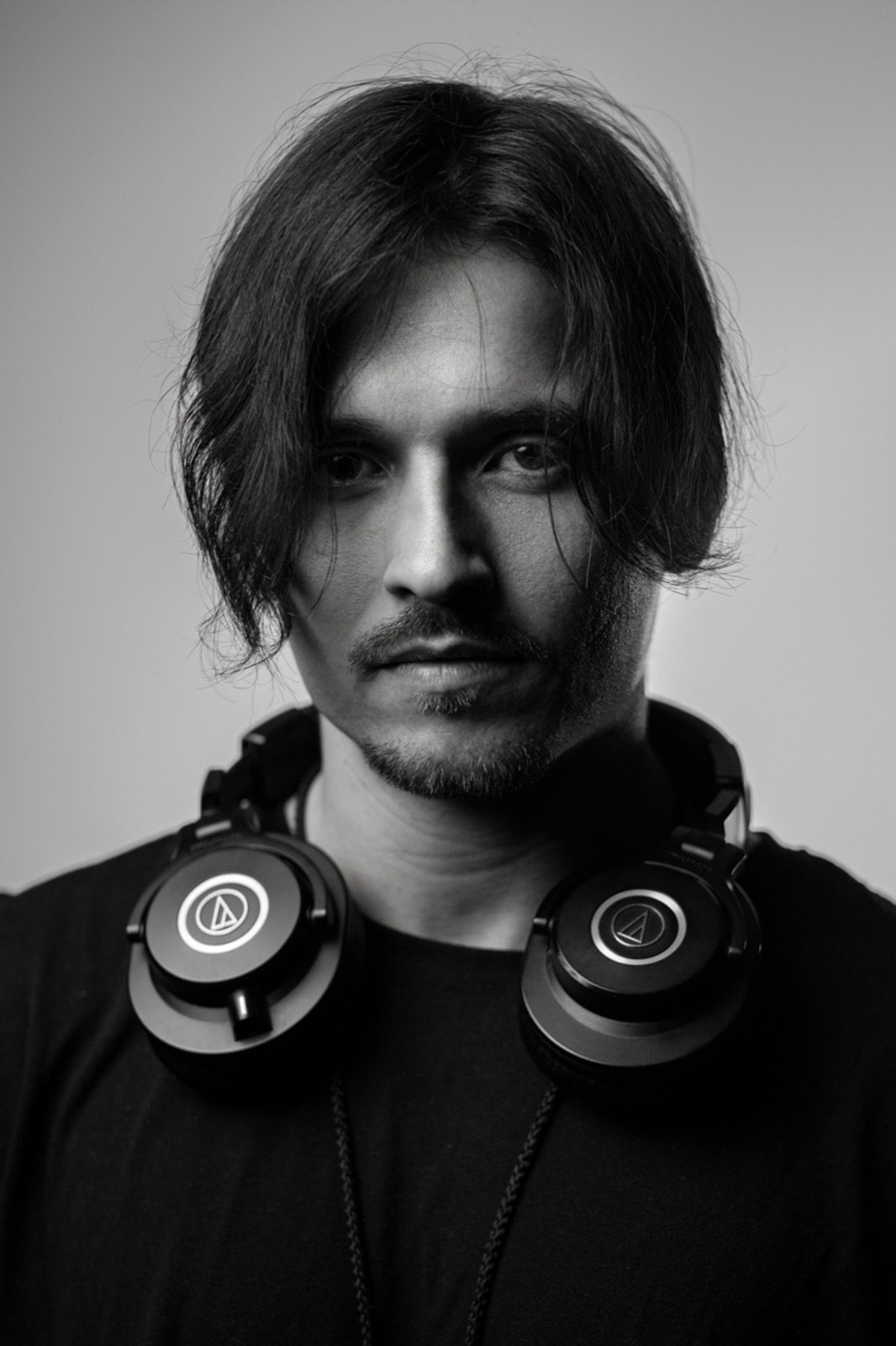 Black-and-white portrait of Vento with headphones around his neck
